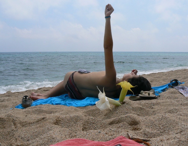Прохожий фотографирует на пляже загорающих без одежды туристок